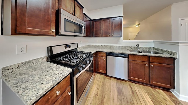 kitchen featuring light stone counters, sink, light wood-type flooring, and appliances with stainless steel finishes