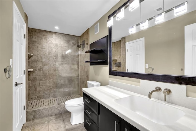 bathroom with visible vents, tiled shower, toilet, and vanity
