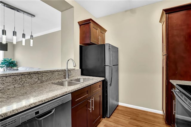 kitchen featuring a sink, dishwashing machine, light stone countertops, and light wood finished floors