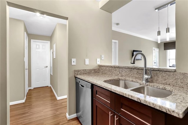 kitchen featuring baseboards, light wood-type flooring, light stone counters, stainless steel dishwasher, and a sink