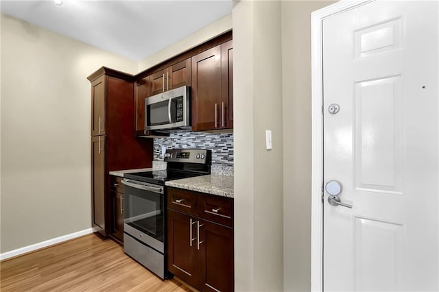 kitchen with baseboards, stainless steel appliances, dark brown cabinets, light wood-style floors, and tasteful backsplash