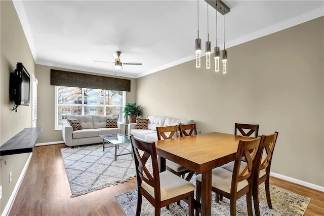 dining space with ceiling fan, baseboards, wood finished floors, and ornamental molding