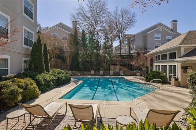community pool with a patio area and a residential view