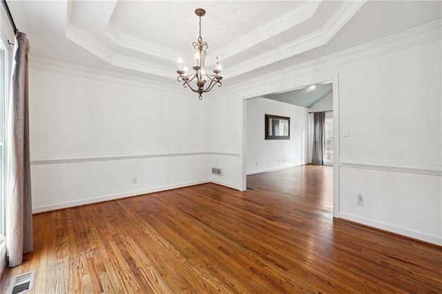 empty room featuring hardwood / wood-style flooring, crown molding, an inviting chandelier, and a tray ceiling