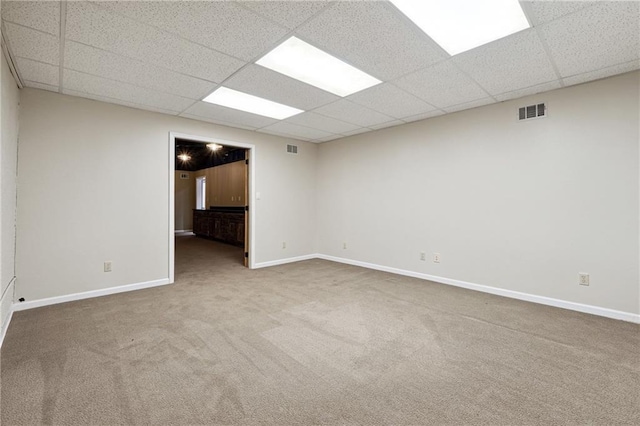 carpeted empty room featuring a drop ceiling