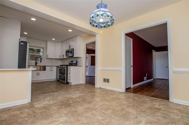 kitchen with stainless steel appliances, decorative light fixtures, sink, and white cabinets