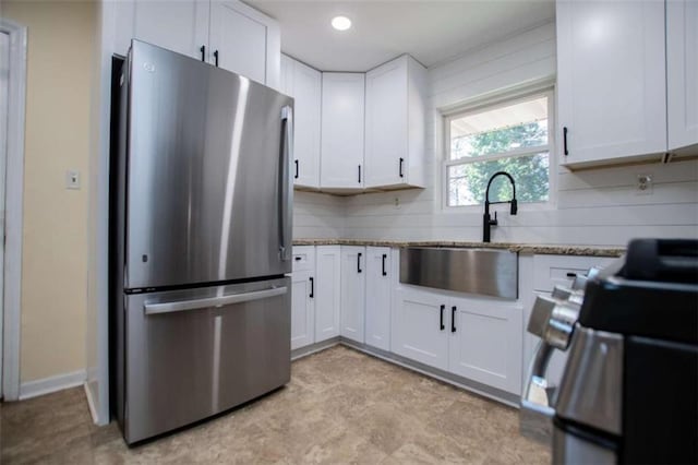 kitchen with sink, white cabinetry, tasteful backsplash, stainless steel appliances, and light stone countertops