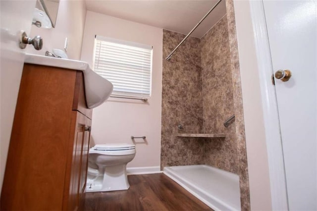 bathroom with tiled shower, vanity, toilet, and hardwood / wood-style floors