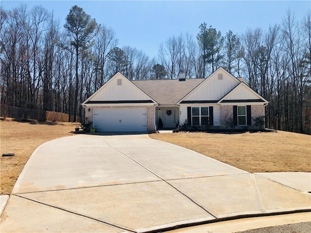 view of front facade with a garage, brick siding, a chimney, and driveway