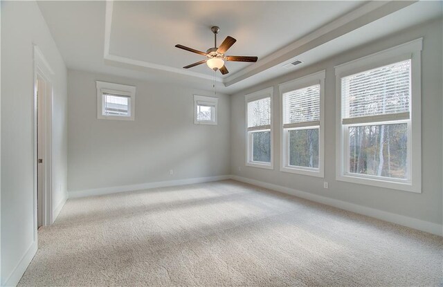 unfurnished room featuring light carpet, visible vents, a raised ceiling, and a ceiling fan