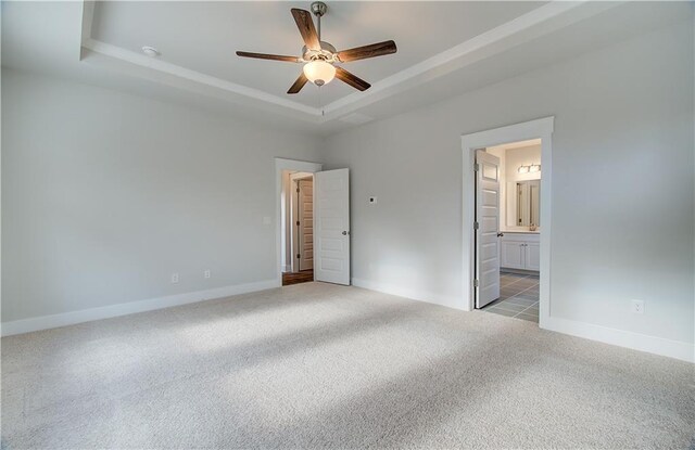 unfurnished bedroom with baseboards, ceiling fan, ensuite bathroom, a raised ceiling, and carpet flooring