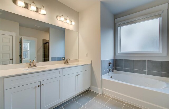 bathroom with a sink, a garden tub, double vanity, and tile patterned floors