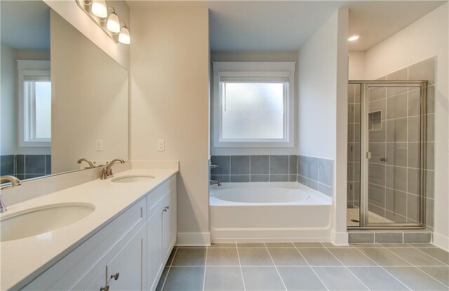 bathroom featuring tile patterned flooring, a stall shower, a garden tub, and a sink