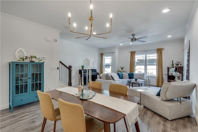 dining room with stairway, light wood finished floors, recessed lighting, ornamental molding, and ceiling fan with notable chandelier