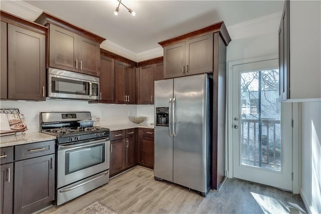 kitchen featuring dark brown cabinetry, ornamental molding, and stainless steel appliances