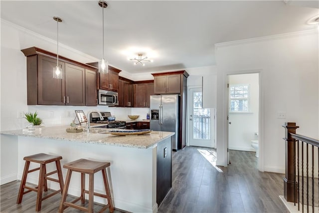 kitchen with dark wood-type flooring, crown molding, light stone counters, decorative light fixtures, and appliances with stainless steel finishes