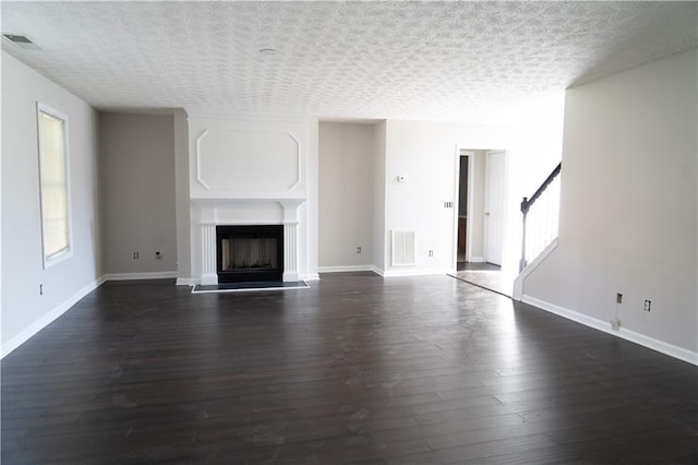 unfurnished living room with a textured ceiling and dark wood-type flooring