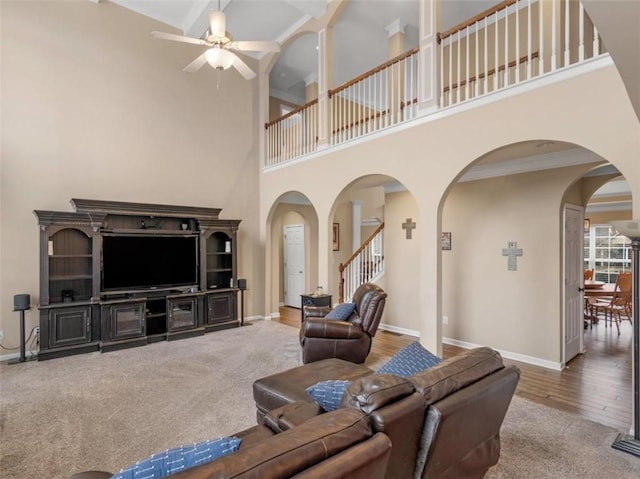 living room featuring hardwood / wood-style flooring, crown molding, a high ceiling, and ceiling fan