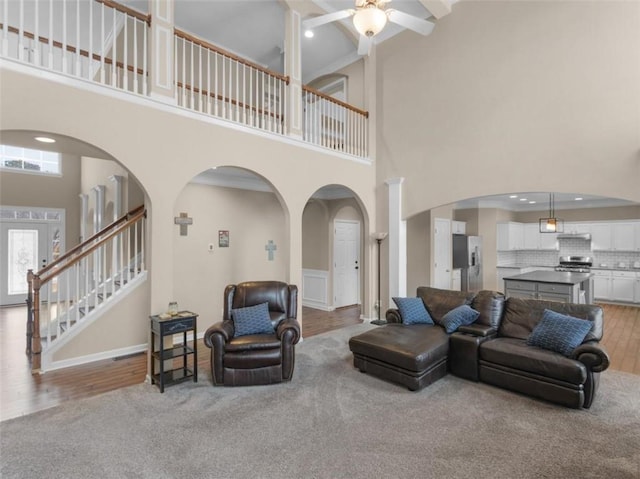 living room featuring ceiling fan, a high ceiling, and light wood-type flooring