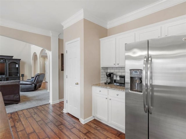 kitchen with dark wood-type flooring, tasteful backsplash, ornamental molding, white cabinets, and stainless steel fridge with ice dispenser