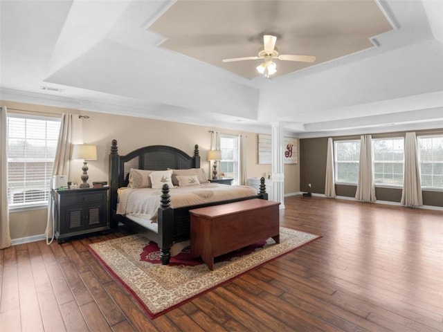 bedroom with a raised ceiling, dark hardwood / wood-style floors, and ceiling fan