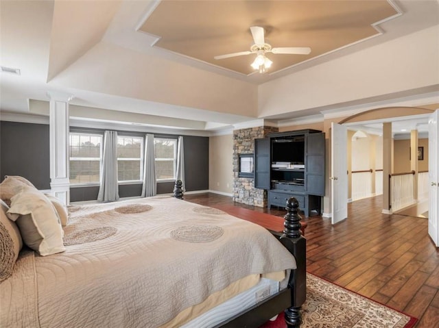 bedroom featuring ornamental molding, dark wood-type flooring, ceiling fan, and a tray ceiling