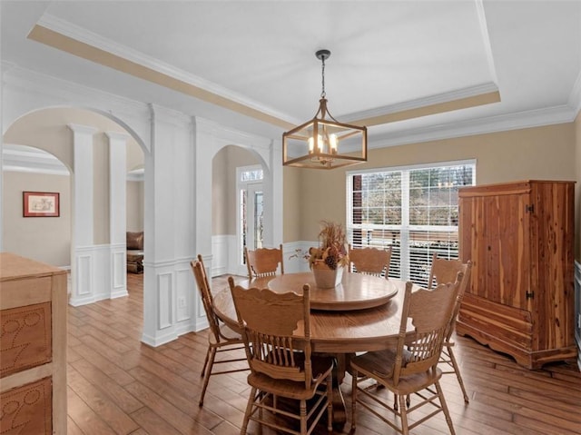 dining room with crown molding, a notable chandelier, light wood-type flooring, and a tray ceiling