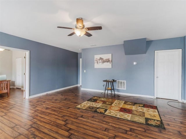 unfurnished living room featuring dark wood-type flooring and ceiling fan