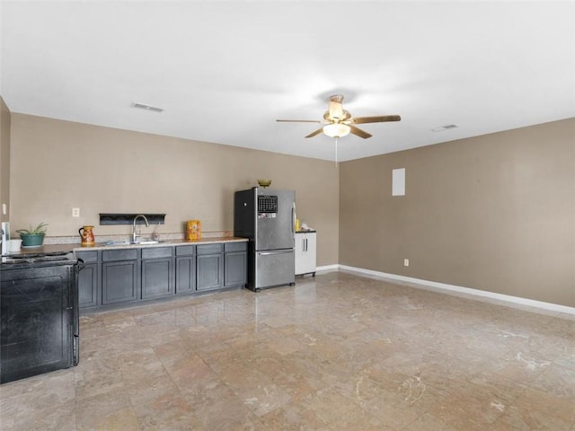 kitchen with sink, stainless steel fridge, ceiling fan, and black range oven