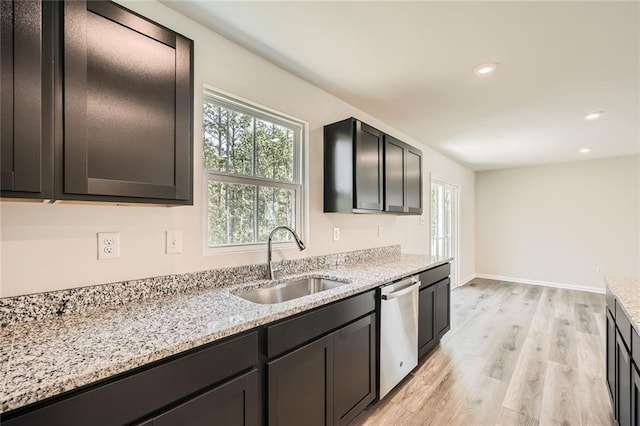kitchen with a sink, light wood finished floors, a healthy amount of sunlight, and dishwasher