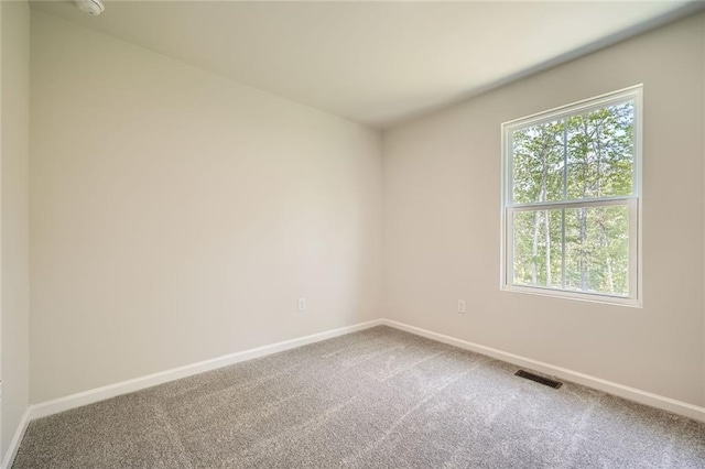 carpeted spare room featuring visible vents and baseboards