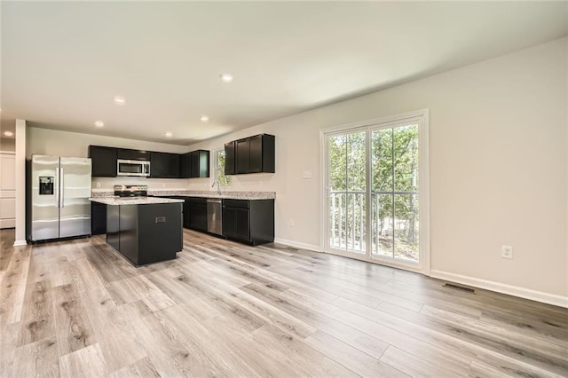 kitchen with stainless steel appliances, light wood-type flooring, visible vents, light countertops, and a kitchen island