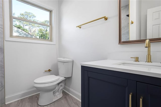 bathroom featuring baseboards, toilet, and vanity