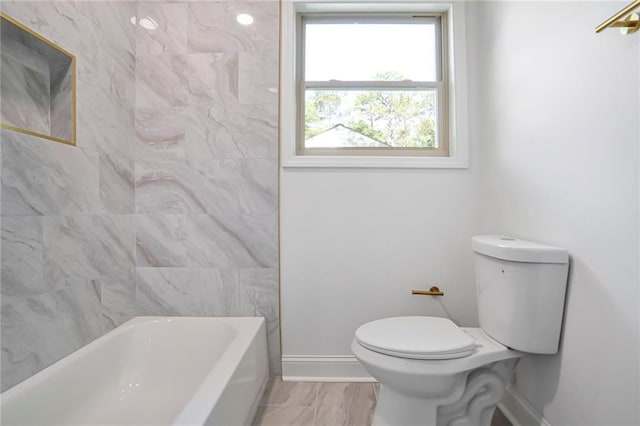 bathroom featuring toilet, baseboards, and shower / bath combination