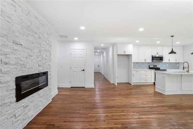 kitchen featuring appliances with stainless steel finishes, white cabinetry, dark wood finished floors, light countertops, and backsplash