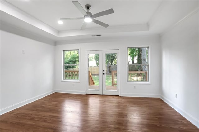 empty room featuring a raised ceiling, wood finished floors, a ceiling fan, and french doors