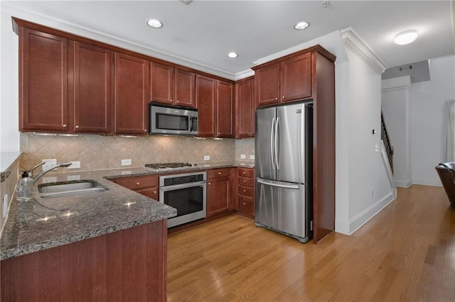 kitchen with sink, stainless steel appliances, tasteful backsplash, light hardwood / wood-style floors, and dark stone counters