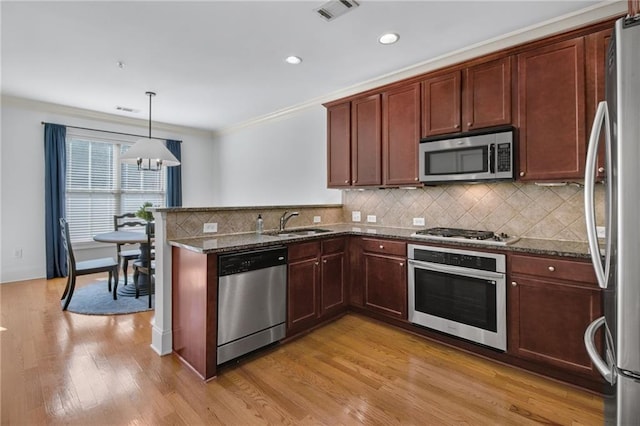 kitchen featuring pendant lighting, sink, dark stone countertops, and appliances with stainless steel finishes