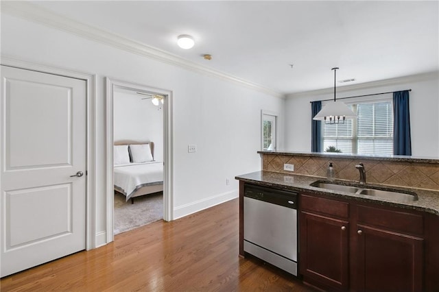 kitchen with sink, hanging light fixtures, stainless steel dishwasher, ornamental molding, and backsplash