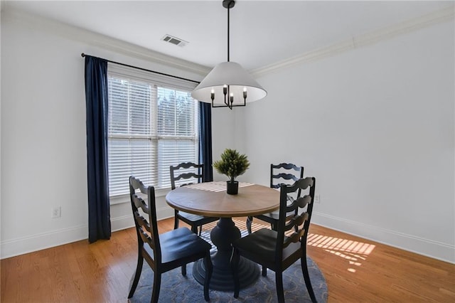 dining space featuring ornamental molding, wood-type flooring, and a chandelier