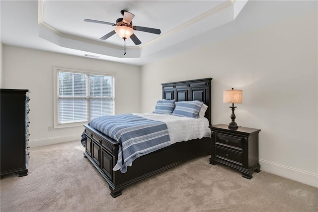 carpeted bedroom with crown molding, ceiling fan, and a tray ceiling