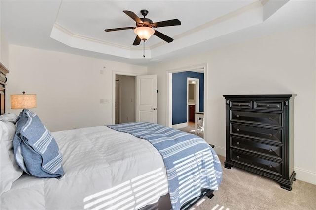 carpeted bedroom with crown molding, ceiling fan, a raised ceiling, and ensuite bath