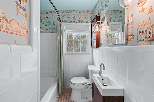 bathroom with wainscoting, tile walls, toilet, and wallpapered walls