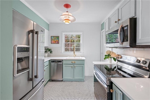 kitchen with ornamental molding, a sink, stainless steel appliances, light countertops, and backsplash