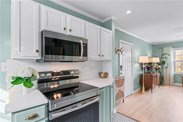 kitchen with decorative backsplash, ornamental molding, stainless steel appliances, light countertops, and light wood-style floors