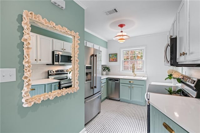 kitchen featuring visible vents, appliances with stainless steel finishes, ornamental molding, light countertops, and a sink