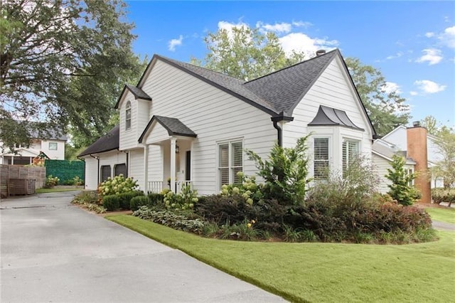 view of side of property with a shingled roof, concrete driveway, a yard, and fence