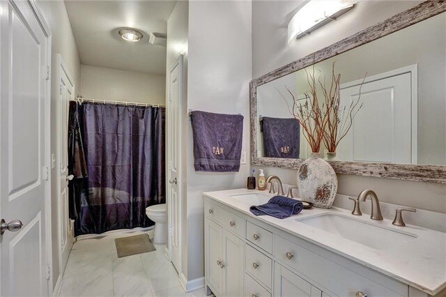 bathroom with dual bowl vanity, toilet, and tile patterned flooring