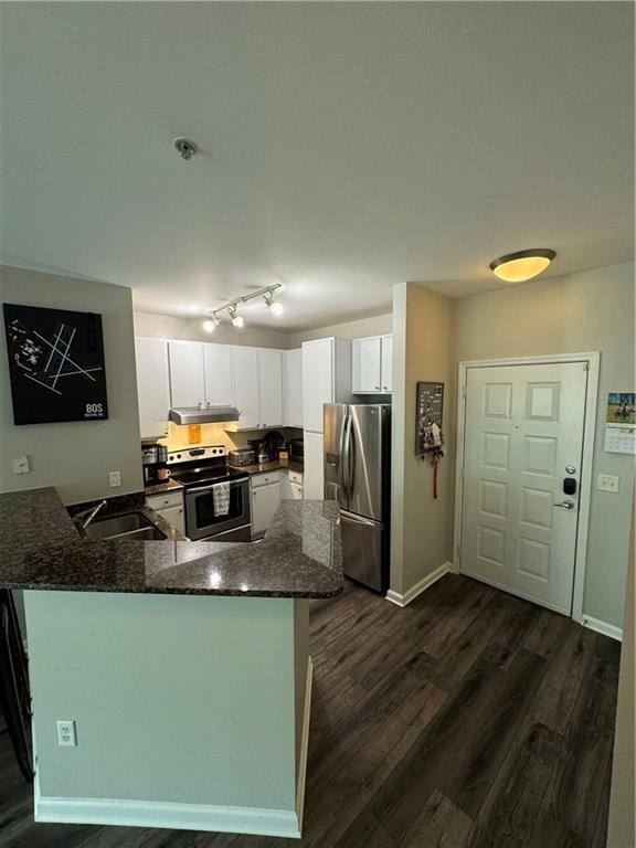 kitchen with appliances with stainless steel finishes, sink, white cabinetry, rail lighting, and kitchen peninsula