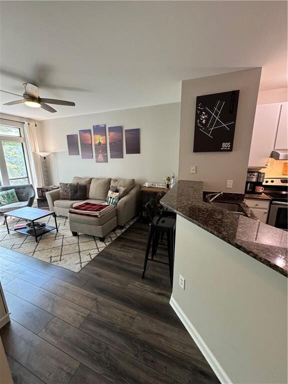 living room featuring ceiling fan, wood-type flooring, and sink